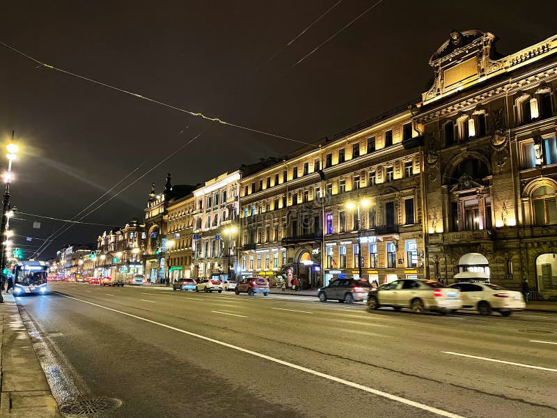 Nevsky Prospekt with moving cars, bus and walking people, illuminated houses. Night St. Petersburg Nevsky Prospekt. Nevsky Prospekt with moving cars, bus and walking people, illuminated houses. Night St. Petersburg Nevsky Prospekt.
