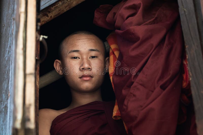 Nyaungshwe, Myanmar - abril de 2019: retrato de un monje budista del novato joven que mira fuera de la ventana fotos de archivo Nyaungshwe, Myanmar - abril de 2019: retrato de un monje budista del novato joven que mira fuera de la ventana fotos de archivo