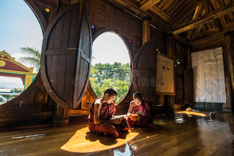 NYAUNGSHWE, MYANMAR - 5 DE OUTUBRO DE 2014: Principiante de Myanmar que lê o livro no monastério de Shwe Yaunghwe Kyaung o templo fotografia de stock royalty free NYAUNGSHWE, MYANMAR - 5 DE OUTUBRO DE 2014: Principiante de Myanmar que lê o livro no monastério de Shwe Yaunghwe Kyaung o templo fotografia de stock royalty free