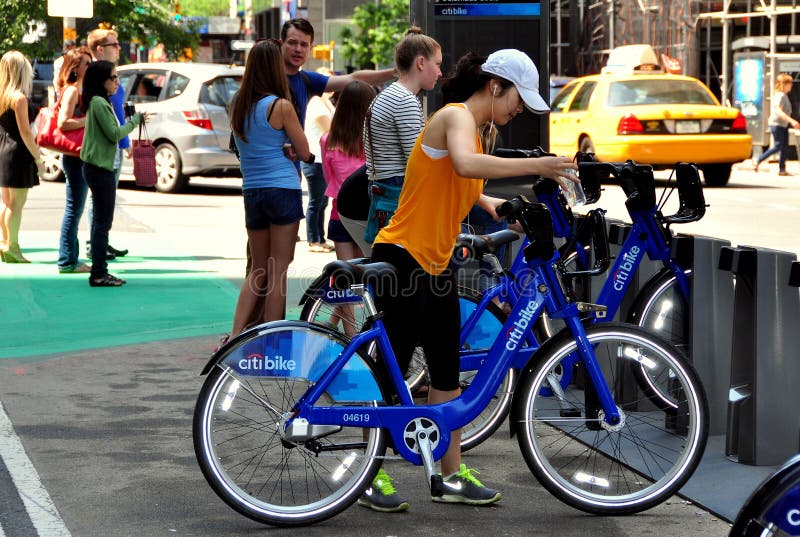 Woman checking out one of the brand new Citibikes from a docking station at 56th Street and Broadway in NYC. Woman checking out one of the brand new Citibikes from a docking station at 56th Street and Broadway in NYC.