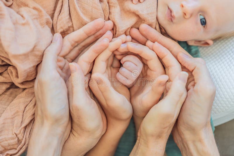 Nyfödd liten hand omgiven av familj. Symbol för kärleksskydd och starka familjeband. Föräldrabarn och royaltyfri fotografi