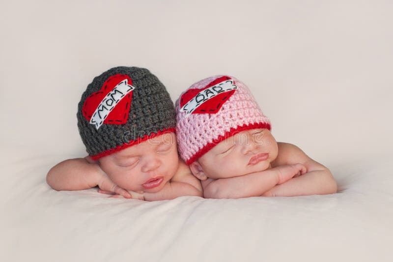 Five week old sleeping boy and girl fraternal twin newborn babies. They are wearing crocheted Love Mom and Love Dad beanies. Five week old sleeping boy and girl fraternal twin newborn babies. They are wearing crocheted Love Mom and Love Dad beanies.