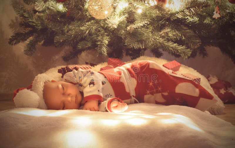 Nyfött behandla som ett barn pojken som sover, och drömma under julträdet som slås in på att sova jul, hänga löst arkivfoton Nyfött behandla som ett barn pojken som sover, och drömma under julträdet som slås in på att sova jul, hänga löst arkivfoton