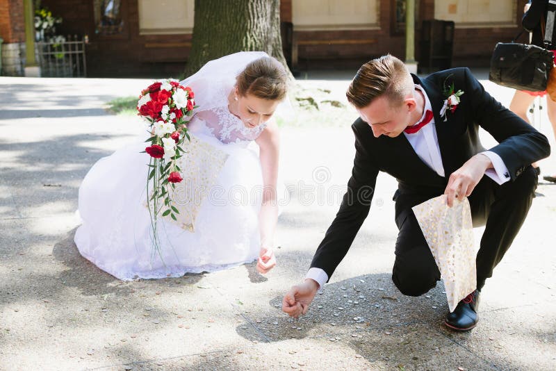Nygifta personer samlar mynt som kastas av bröllopgästerna royaltyfri fotografi Nygifta personer samlar mynt som kastas av bröllopgästerna royaltyfri fotografi