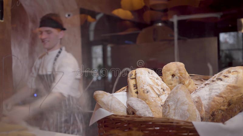 Nytt bakat bröd som ligger i korgen i förgrunden på tabellen i modernt restaurangslut upp Yrkesmässig kock