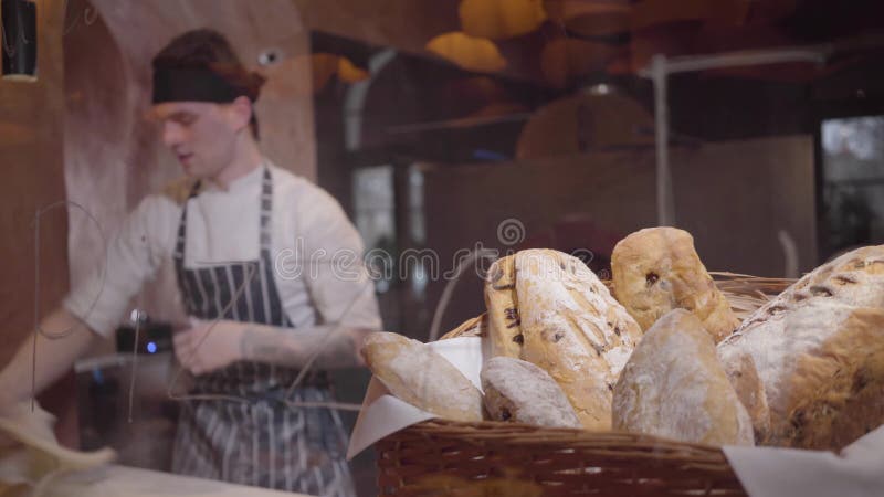 Nytt bakat bröd som ligger i korgen i förgrunden på tabellen i modernt restaurangslut upp Yrkesmässig kock