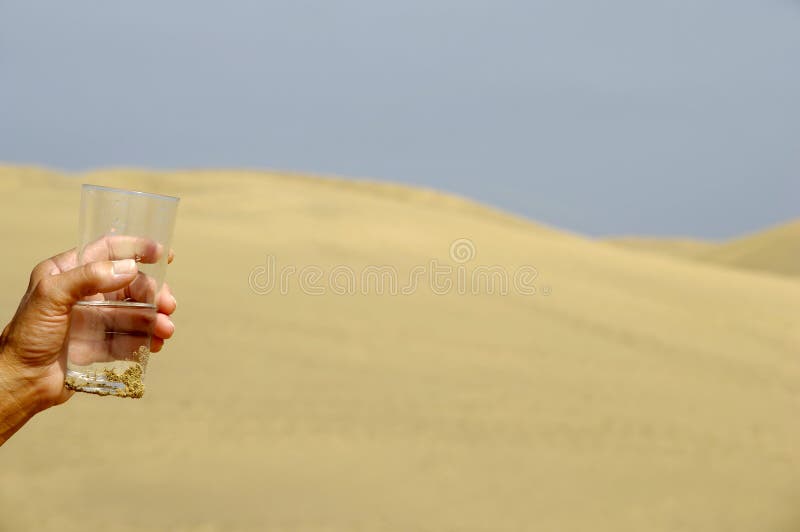 Hand is holding a fresh glass of cold water in desert. Hand is holding a fresh glass of cold water in desert.