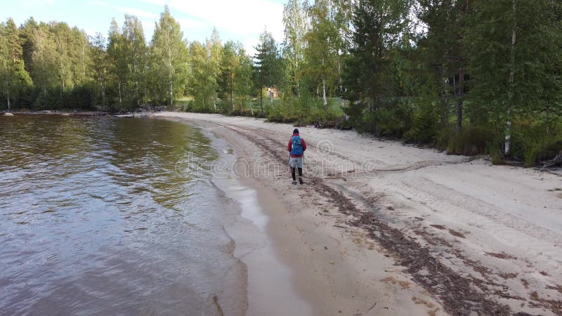 Nähe eines Reisenden, der den Strand im koli Nationalpark im östlichen Finland entlang spaziert und seinen Abenteuerurlaub fortset