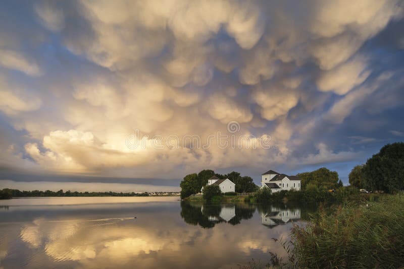 När du bedövar dramatisk mammatus fördunklar bildande över sjölandskap royaltyfria bilder