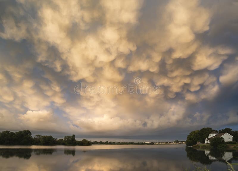 När du bedövar dramatisk mammatus fördunklar bildande över sjölandskap royaltyfri bild