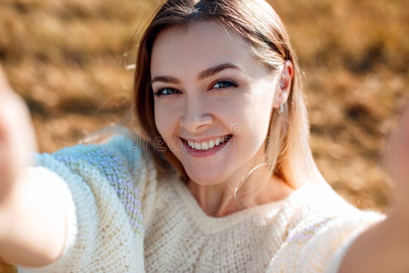 När du ler den unga kvinnan gör selfie och att tycka om naturen i höstsäsong royaltyfri fotografi När du ler den unga kvinnan gör selfie och att tycka om naturen i höstsäsong royaltyfri fotografi