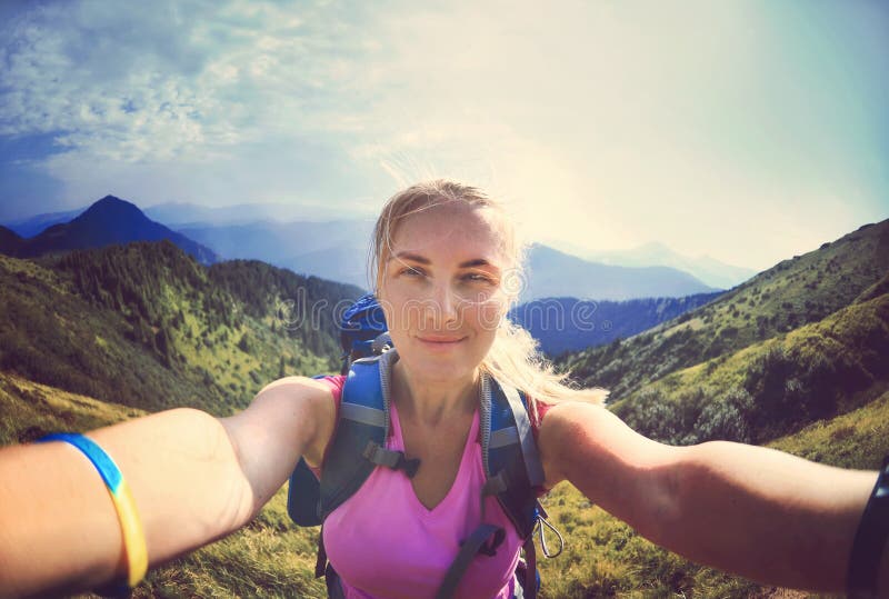 När du ler den unga kvinnan tar en selfie på bergmaximum arkivbild När du ler den unga kvinnan tar en selfie på bergmaximum arkivbild