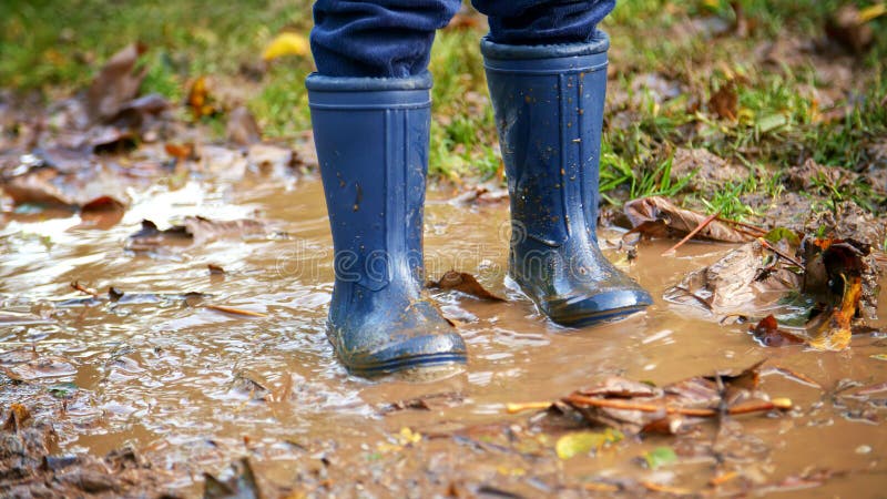 Nära barn som hade Wellington-bollar i Puddle på gång genom höstens landsida royaltyfri bild