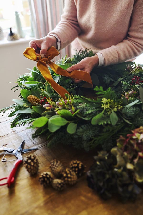 Nära kvinnor som tillverkar och dekorerar den fetiva julkrans på bordet hemma royaltyfri fotografi