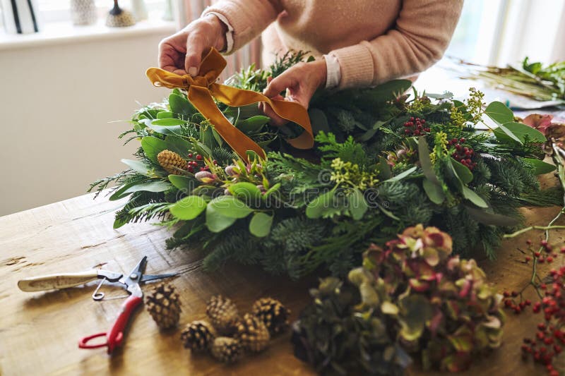 Nära kvinnor som tillverkar och dekorerar den fetiva julkrans på bordet hemma fotografering för bildbyråer