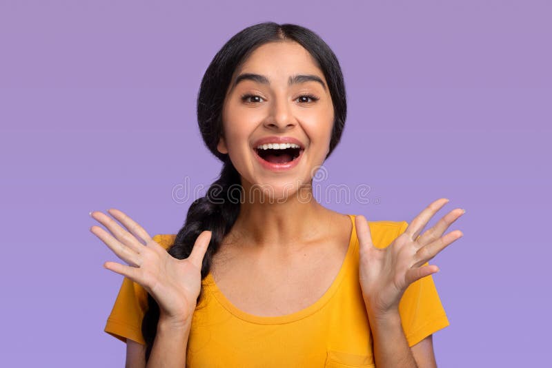 Positive Emotions. Portrait of excited indian woman screaming with joy, isolated over purple studio background. Sale And Discount Concept. Emotional young female model shouting, spreading hands. Positive Emotions. Portrait of excited indian woman screaming with joy, isolated over purple studio background. Sale And Discount Concept. Emotional young female model shouting, spreading hands