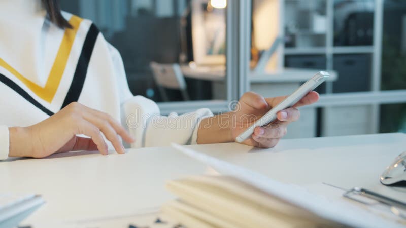 Nära upp kvinnans händer med hjälp av datortangentbord och sedan med hjälp av smarttelefon på arbetsplatsen