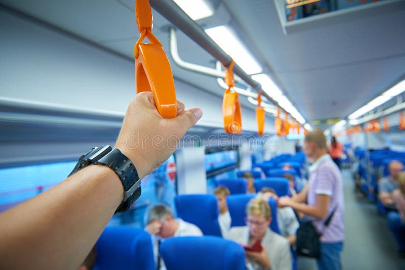 Nära övre sikt på manhanden som rymmer handtaget av drevledstången och den blured drevinre och passagerare i bakgrunden royaltyfri fotografi Nära övre sikt på manhanden som rymmer handtaget av drevledstången och den blured drevinre och passagerare i bakgrunden royaltyfri fotografi