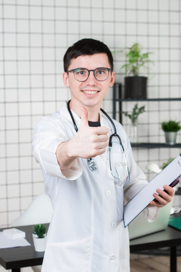 Nära övre stående av att le doktorn som rekommenderar den nya vägen av behandling, genom att visa upp tummen royaltyfri foto Nära övre stående av att le doktorn som rekommenderar den nya vägen av behandling, genom att visa upp tummen royaltyfri foto