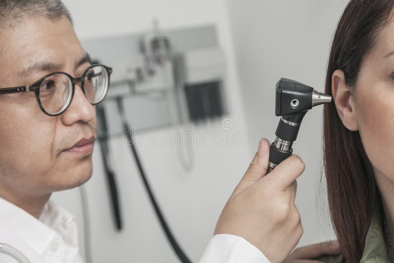 Närbild av doktorn som kontrollerar öronen av en patient arkivbild Närbild av doktorn som kontrollerar öronen av en patient arkivbild
