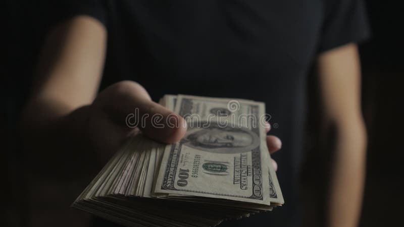 Närbild av en man som ger en trumma av dollarräkningar Begreppet av timpenningar välgörenhet