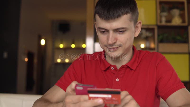Närbild av en man som köper online-bruk en telefon och en kreditkort arkivfilmer