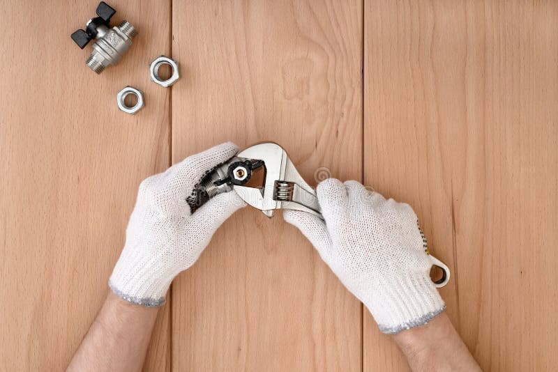 Närbilden av mannen räcker att rymma bollventilen och en skiftnyckel royaltyfria foton Närbilden av mannen räcker att rymma bollventilen och en skiftnyckel royaltyfria foton