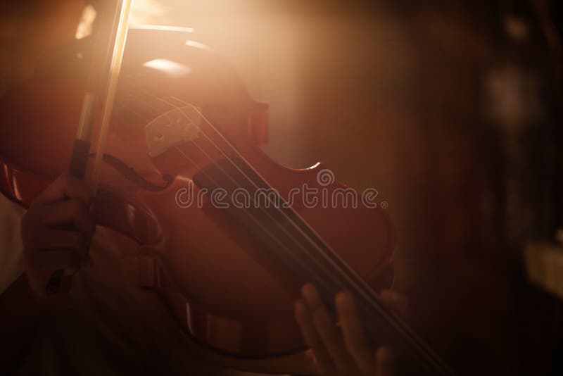 Närbildskottlilla flickan som spelar fiolorkesterinstrumental med varm signal och mörker och korn för tändande effekt, bearbetade
