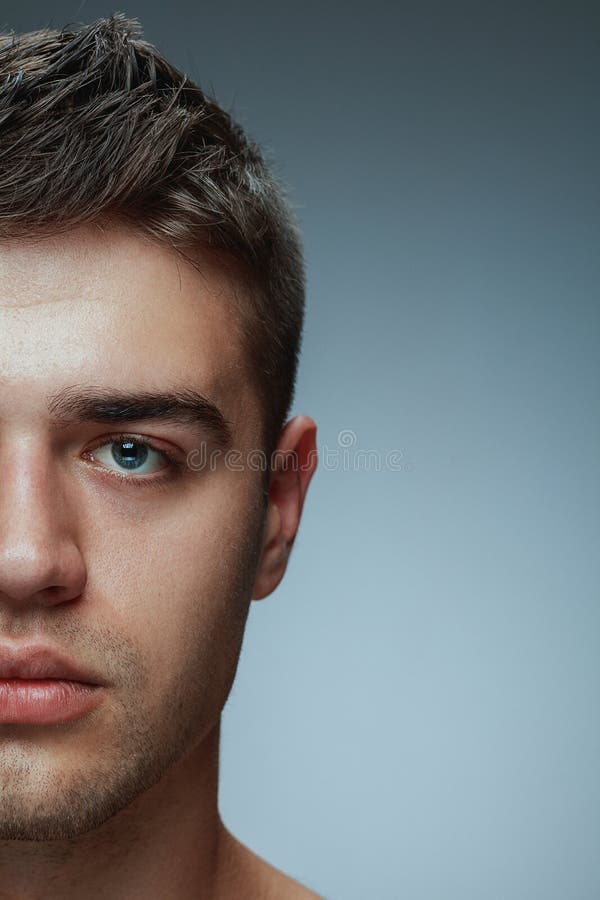 Närbildstående av den unga mannen som isoleras på grå studiobakgrund royaltyfri fotografi Närbildstående av den unga mannen som isoleras på grå studiobakgrund royaltyfri fotografi