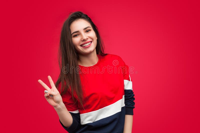 Nätt flicka som visar två fingrar på rött arkivfoto Nätt flicka som visar två fingrar på rött arkivfoto