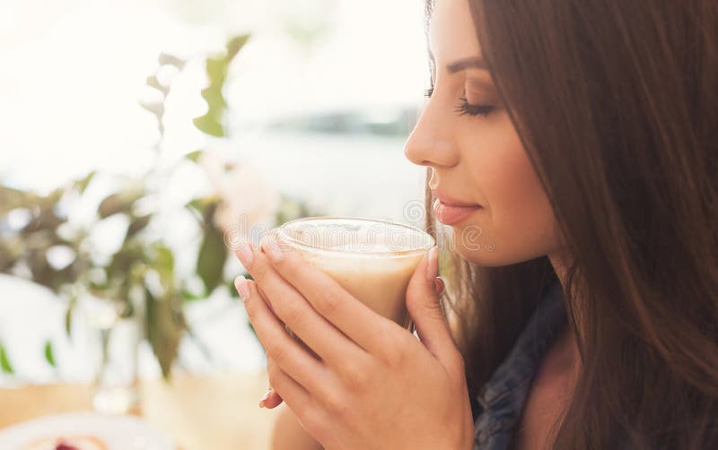 Nätt kvinna som luktar aromatiskt kaffe i morgonen arkivbilder