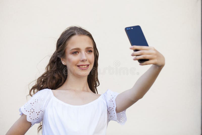 Nätt ung brunettkvinna som gör selfie på smartphonen arkivfoton Nätt ung brunettkvinna som gör selfie på smartphonen arkivfoton