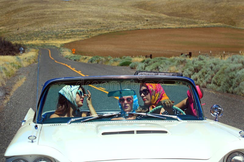 Three attractive pretty girls riding in a convertible with the top down out on a desolate country road. Shallow depth of field. Three attractive pretty girls riding in a convertible with the top down out on a desolate country road. Shallow depth of field.