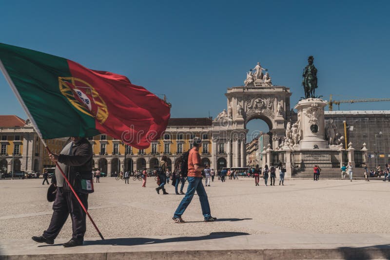 Någon rymmer en jätte- flagga av Portugal på PraÃ§aen gör den ComÃ©rcio kommersfyrkanten i i stadens centrum Lissabon