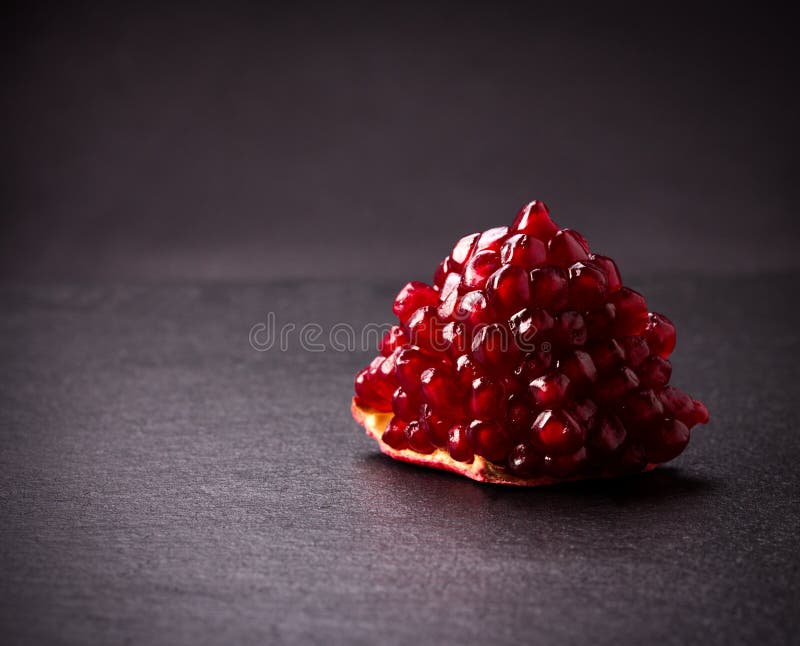 Some red juicy pomegranate, whole and broken, on black slate plate. Some red juicy pomegranate, whole and broken, on black slate plate