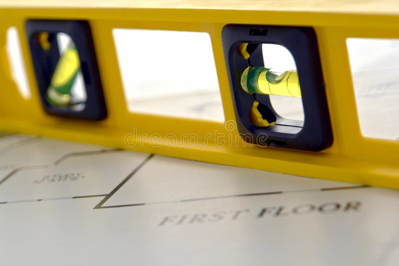 Construction bubble spirit level tool over new house builder construction floor plan. Construction bubble spirit level tool over new house builder construction floor plan