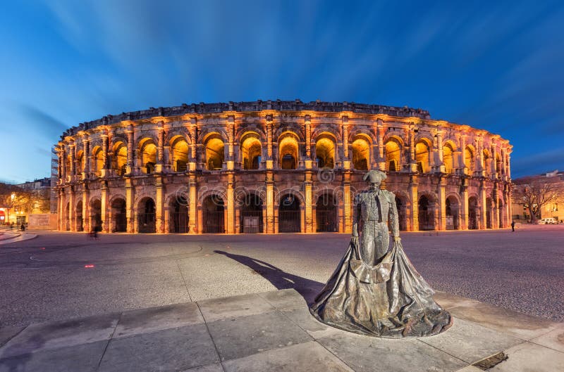 Nimes, France. Roman amphitheater Arena of Nimes at dusk and monument to bullfighter. Nimes, France. Roman amphitheater Arena of Nimes at dusk and monument to bullfighter
