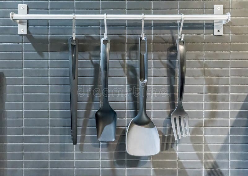 Nödvändig köksgeråd som hänger med den rostfria kroken på silver arkivbilder Nödvändig köksgeråd som hänger med den rostfria kroken på silver arkivbilder