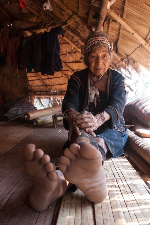 Nördlich von Thailand während des heißen Sommers Eine alte Frau von der Akha-Ethnie, von den Resten im Schatten ihres Hauses gema lizenzfreies stockbild Nördlich von Thailand während des heißen Sommers Eine alte Frau von der Akha-Ethnie, von den Resten im Schatten ihres Hauses gema lizenzfreies stockbild