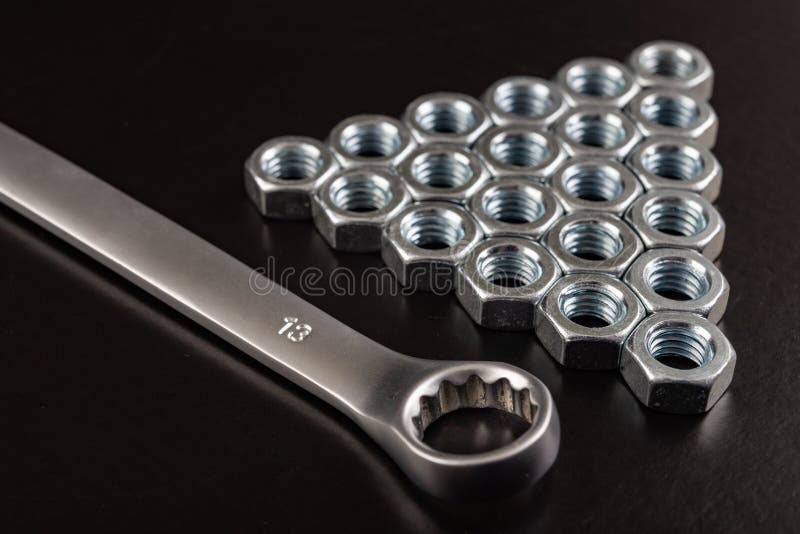 Nickel-plated nuts and wrenches on a workshop table. Tools in a mechanical workshop. Dark background, black, chrome, construction, cylinder, engineering, equipment, facet, industry, isolated, key, metal, metallic, metallurgy, mirror, object, responsibility, rotation, screw, sharpen, shine, shiny, steel, technology, twist, unscrewing, white. Nickel-plated nuts and wrenches on a workshop table. Tools in a mechanical workshop. Dark background, black, chrome, construction, cylinder, engineering, equipment, facet, industry, isolated, key, metal, metallic, metallurgy, mirror, object, responsibility, rotation, screw, sharpen, shine, shiny, steel, technology, twist, unscrewing, white