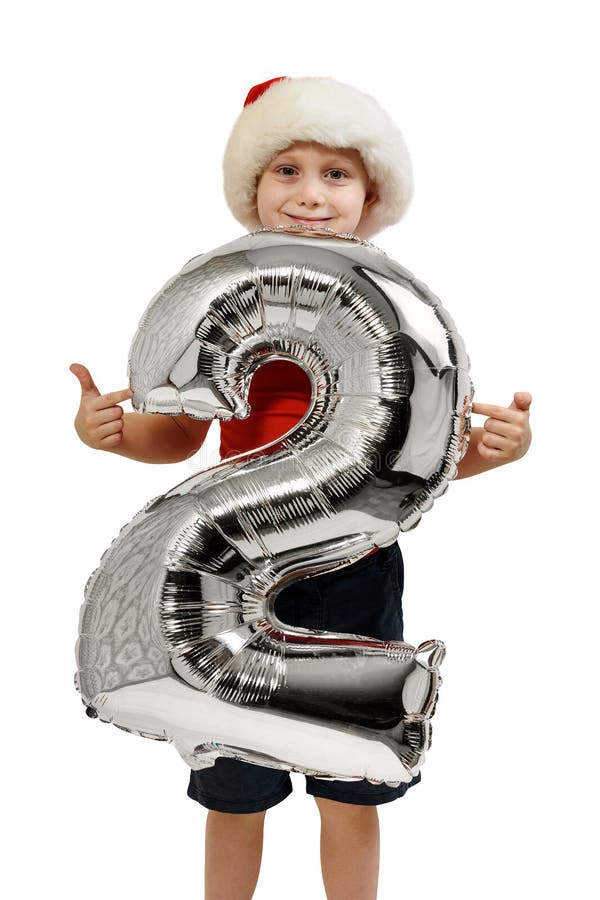 Número 2 de um balão prateado nas mãos de um menino louro num chapéu vermelho de Papai Noel Fundo branco foto de stock Número 2 de um balão prateado nas mãos de um menino louro num chapéu vermelho de Papai Noel Fundo branco foto de stock
