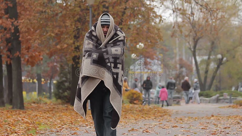 Nędzny biednego człowieka odprowadzenie w miasto parku zakrywającym od zimna z podławą koc
