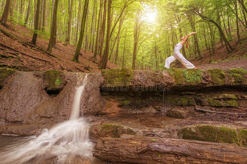O abrandamento, mulher pratica a ioga na cachoeira foto de stock O abrandamento, mulher pratica a ioga na cachoeira foto de stock