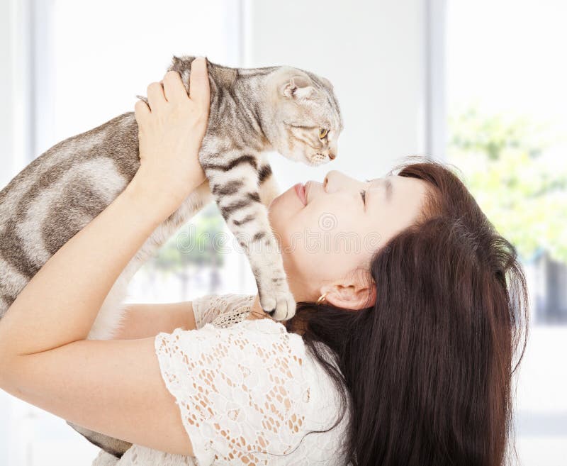 Mulher bonita abraça e beija o seu gato fotografia de stock royalty free