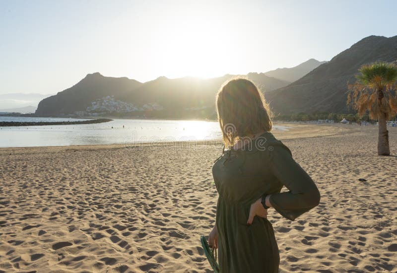 O adolescente espiritual de vestido verde admira o pôr do sol e a cidade marinha numa colina em Tenerife A loira romântica olha foto de stock O adolescente espiritual de vestido verde admira o pôr do sol e a cidade marinha numa colina em Tenerife A loira romântica olha foto de stock