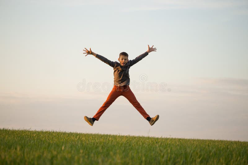 O adolescente está voando sobre o campo no por do sol fotos de stock O adolescente está voando sobre o campo no por do sol fotos de stock