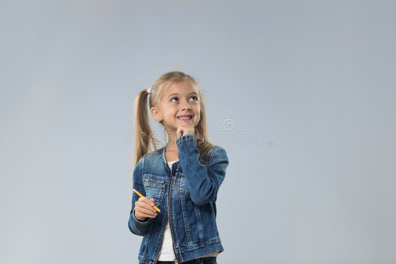 O adolescente pequeno no revestimento das calças de brim, criança pequena que olha acima para copiar o espaço pensa a posse Chin fotografia de stock O adolescente pequeno no revestimento das calças de brim, criança pequena que olha acima para copiar o espaço pensa a posse Chin fotografia de stock