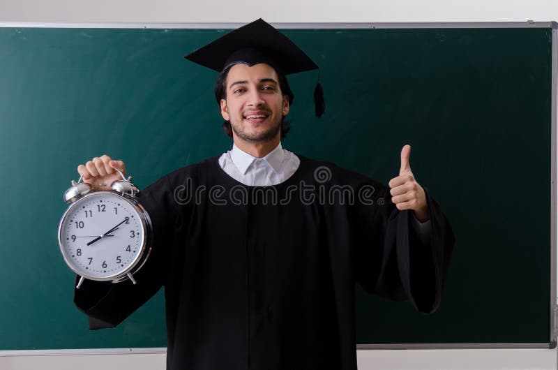 O aluno diplomado na frente da placa verde imagens de stock O aluno diplomado na frente da placa verde imagens de stock