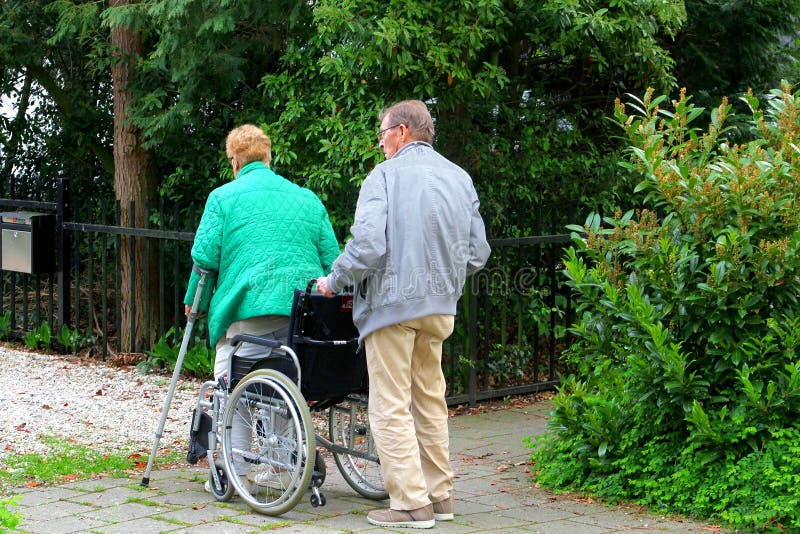 O ancião ajuda sua esposa em uma cadeira de rodas, Países Baixos