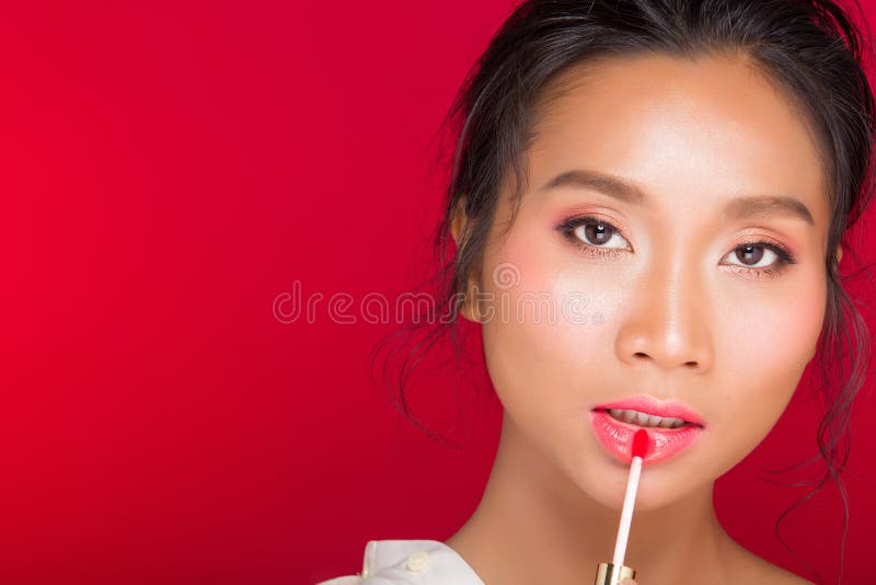 O asiático bronzeou-se a mulher da pele com os bordos fortes do vermelho da cor fotografia de stock royalty free O asiático bronzeou-se a mulher da pele com os bordos fortes do vermelho da cor fotografia de stock royalty free